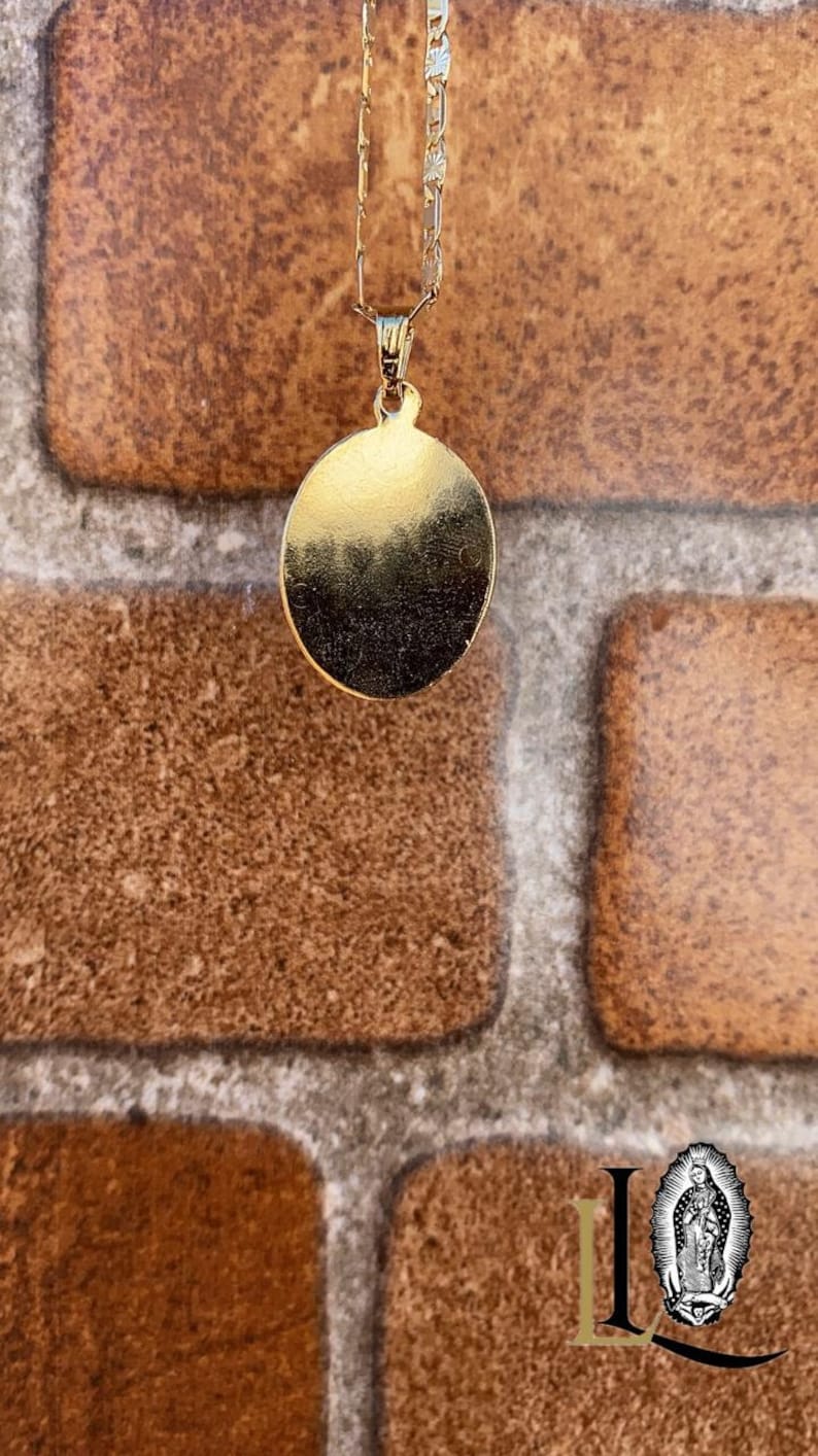 May include: A gold chain necklace with a round pendant. The pendant is smooth and has a shiny finish.