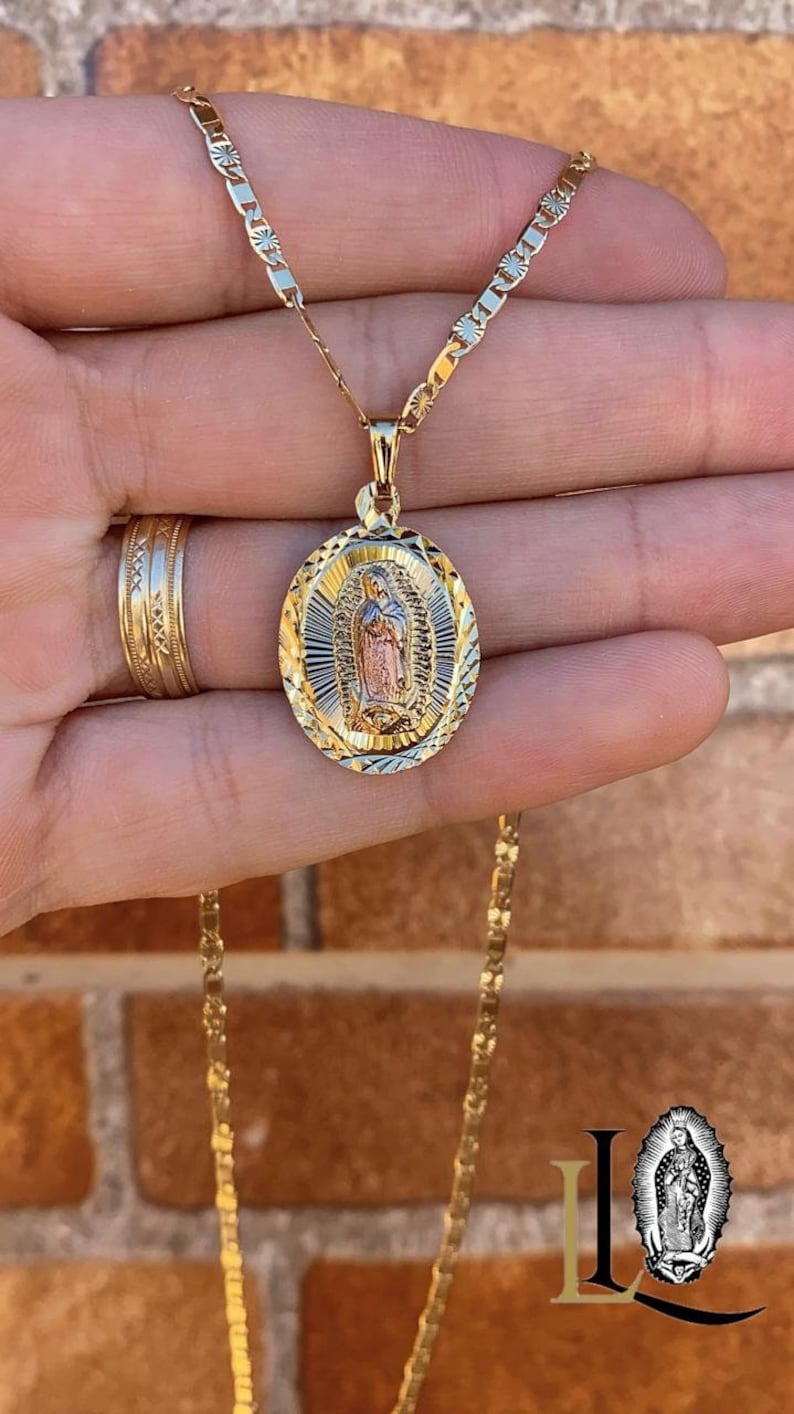 May include: A gold chain necklace with a pendant featuring a detailed image of the Virgin Mary. The pendant is oval-shaped and has a textured, diamond-cut design.