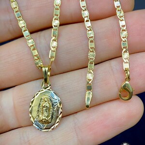 May include: A gold chain necklace with a pendant featuring a depiction of the Virgin Mary. The chain is a delicate, patterned design.