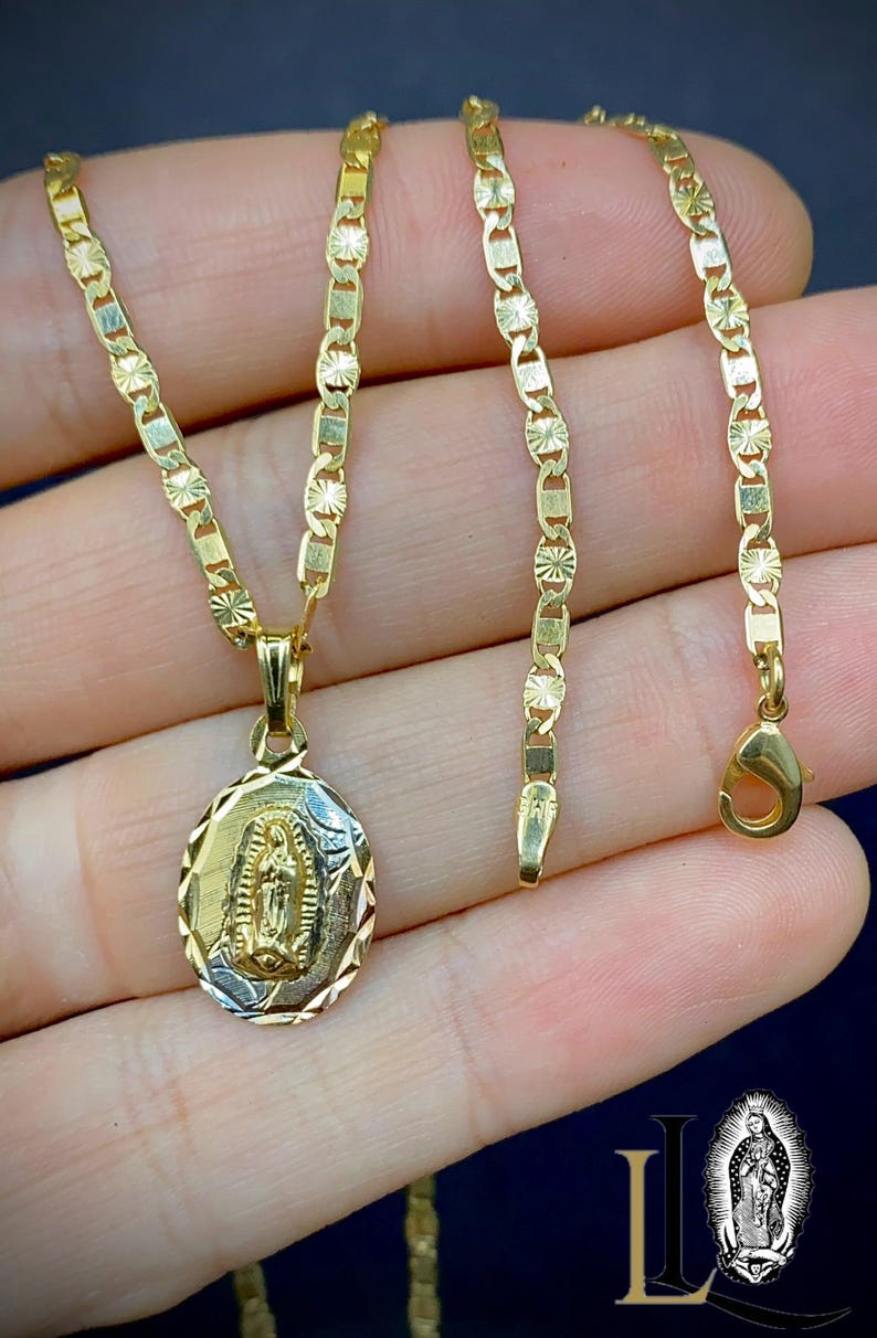 May include: A gold chain necklace with a pendant featuring a depiction of the Virgin Mary. The chain is a delicate, patterned design.