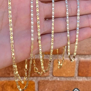 May include: Four gold chains with a diamond-shaped pattern on a hand. The chains are different lengths and are all made of gold.