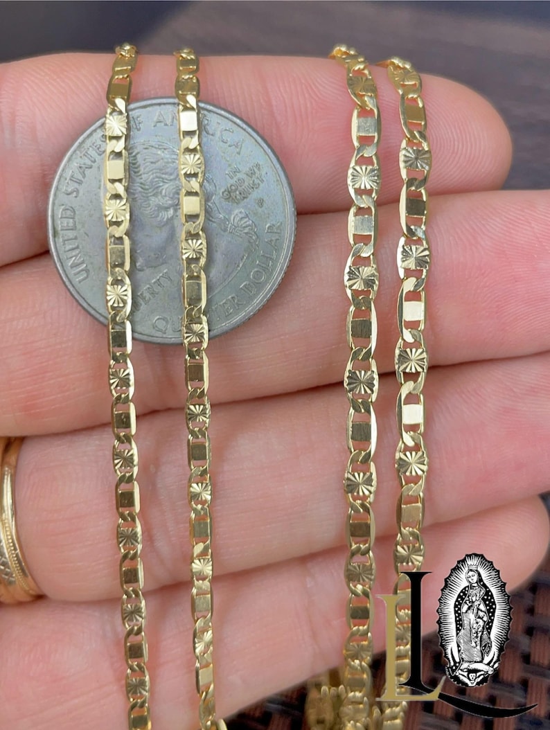 May include: Close-up of three gold-colored necklaces with a delicate, repeating pattern of rectangular and star-shaped links. A U.S. quarter coin is next to the necklaces for size comparison. The necklaces are displayed on a neutral background.