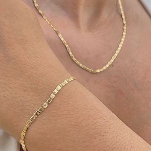 May include: A gold chain necklace and bracelet with a delicate, textured design. The necklace is worn around the neck and the bracelet is worn on the wrist.