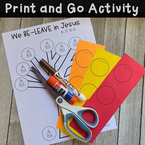 May include: A printable activity sheet with a tree outline and the words "We BE-LEAVE in Jesus ACTS 16:31".  The sheet is surrounded by craft supplies, including scissors, glue, and colored paper circles.