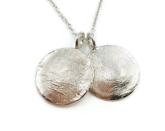 May include: A silver necklace with two round pendants. Each pendant has a unique fingerprint design.