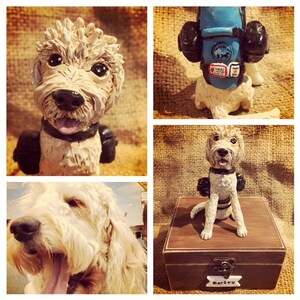 May include: A custom-made clay sculpture of a dog wearing a backpack. The sculpture is sitting on a wooden box with the name "Barley" engraved on it.