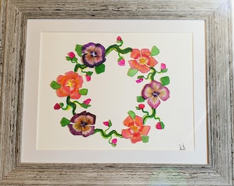 May include: A watercolor painting of a floral wreath with pink, purple, and green flowers. The wreath is framed in a light wood frame.