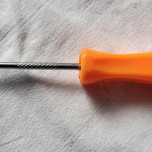 May include: An orange Snap-on flathead screwdriver. The handle is a bright orange color, and the metal shaft is silver. The text "Snap-on S00304 USA" is printed on the handle. The screwdriver is lying on a white surface.