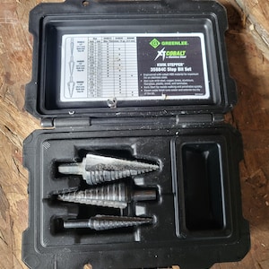 May include: A black plastic case containing a Greenlee Cobalt Kwik Stepper 35884C Step Bit Set. The case is open, revealing three silver step drill bits and a chart with measurements in inches. The text "300que" is visible on one of the bits.