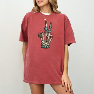 a woman wearing a red t - shirt with an image of a hand holding a
