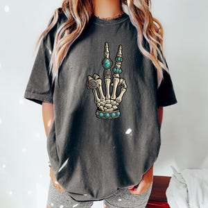 a woman wearing a t - shirt with a skeleton hand on it