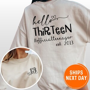 A white sweatshirt with black text and a number 13 printed on it.