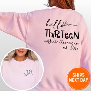 A woman wearing a pink sweatshirt with text printed on the back.