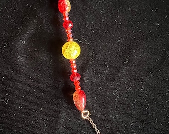 May include: A red and yellow beaded necklace with a gold star charm at the end.