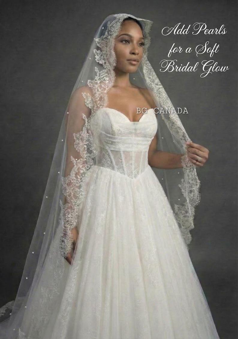 May include: A white bridal gown with a sweetheart neckline and a tulle skirt. The dress is paired with a long, sheer veil adorned with lace trim and small pearls. Text on the image reads "Add Pearls for a Soft Bridal Glow" and "BG CANADA".