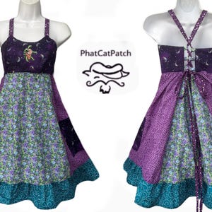 May include: Purple and teal patchwork dress with a moon and star print on the bodice and a floral print on the skirt. The dress has a tie-up back and a ruffled hem.