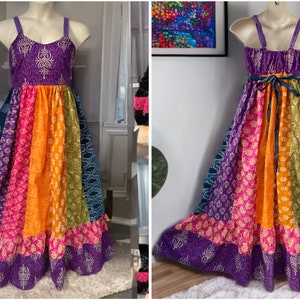 May include: A long, multi-colored, patchwork dress with a purple bodice and a rainbow-colored skirt. The dress has a tie at the back and is made of a soft, flowing fabric.