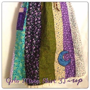 May include: A multi-colored patchwork skirt with a crescent moon applique. The skirt is made from different fabrics with floral and polka dot patterns. The skirt is labeled "Girls Moon Skirt 3T - up".