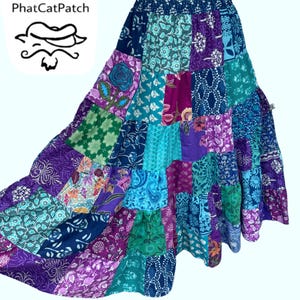 May include: A long, patchwork skirt with a mix of floral and paisley patterns in shades of purple, blue, and green. The skirt has a wide waistband and a flowing silhouette.