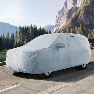 May include: A gray car cover is protecting a car from the elements. The car cover is made of a water-resistant material and has a drawstring closure. The car is parked in a scenic location with mountains in the background.