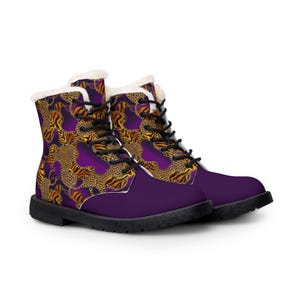 May include: A pair of purple combat boots with a faux fur lining. The boots feature a pattern of leopard and tiger print in shades of brown and gold. The boots have black laces and a black sole.