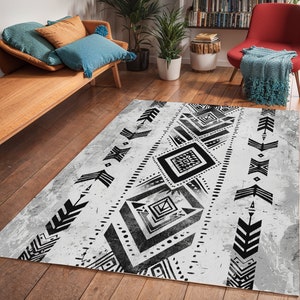 K&ouml;nnte beinhalten: Schwarz-wei&szlig;er geometrischer Teppich mit einem abgenutzten, Vintage-Look. Der Teppich hat eine zentrale Diamantform mit kleineren Diamantformen und Pfeilmotiven.