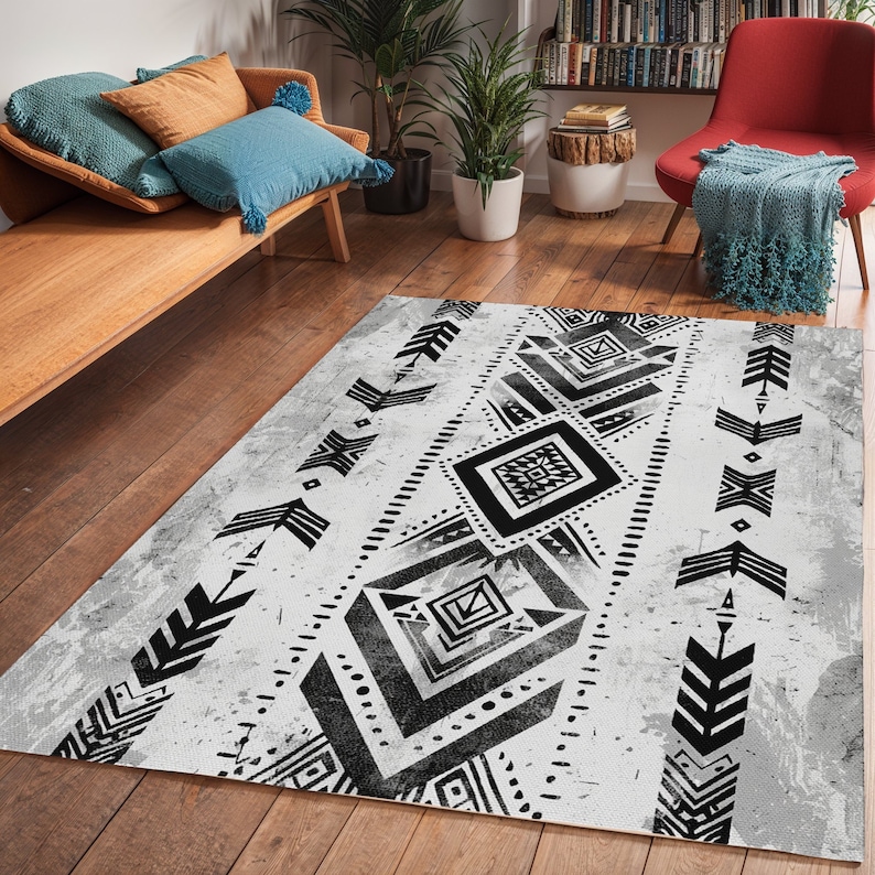 K&ouml;nnte beinhalten: Schwarz-wei&szlig;er geometrischer Teppich mit einem abgenutzten, Vintage-Look. Der Teppich hat eine zentrale Diamantform mit kleineren Diamantformen und Pfeilmotiven.