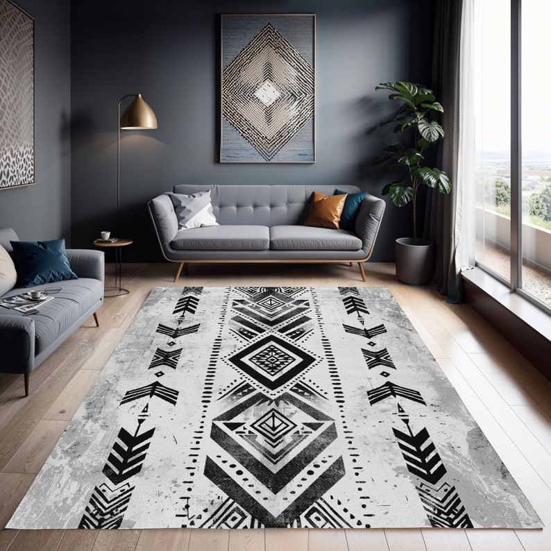 K&ouml;nnte beinhalten: Schwarz-wei&szlig;er geometrischer Teppich mit einem abgenutzten wei&szlig;en Hintergrund. Der Teppich hat eine zentrale Diamantform mit Pfeilen und anderen geometrischen Formen auf beiden Seiten.