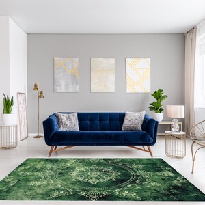 May include: A green area rug with a white mandala design in the center. The rug is in a living room with a blue velvet sofa, a gold chair, and a gold floor lamp.