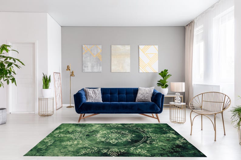 May include: A green area rug with a white mandala design in the center. The rug is in a living room with a blue velvet sofa, a gold chair, and a gold floor lamp.