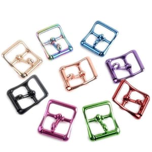 Puede incluir: Surtido de hebillas de rodillo de metal de colores. Las hebillas son de varios colores, incluyendo negro, dorado, verde, morado, rosa y azul.