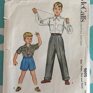 以下が含まれることがあります： 男の子のスラックス、シャツ、ショートパンツ用のヴィンテージのMcCall's裁縫パターン。パターンはサイズ10で、35セントです。パターンには、服を着た2人の男の子が描かれています。左側の男の子は、チェック柄のシャツ、ショートパンツ、茶色の靴を履いています。右側の男の子は、白いボタンダウンシャツ、灰色のスラックス、茶色の靴を履いています。