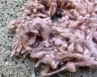 May include: A close-up of a pile of pink fluffy yarn. The yarn is soft and textured, and it appears to be made of wool.