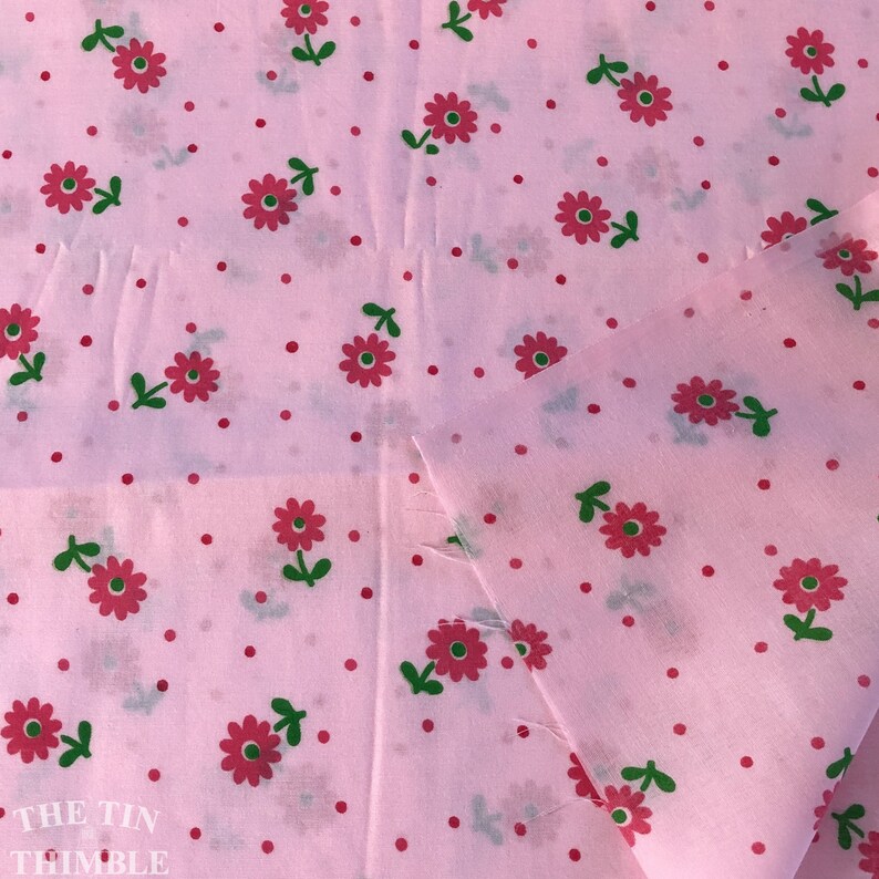 K&ouml;nnte beinhalten: Rosafarbener Stoff mit einem sich wiederholenden Muster aus kleinen roten Bl&uuml;ten mit gr&uuml;nen Stielen und winzigen rosa Punkten.