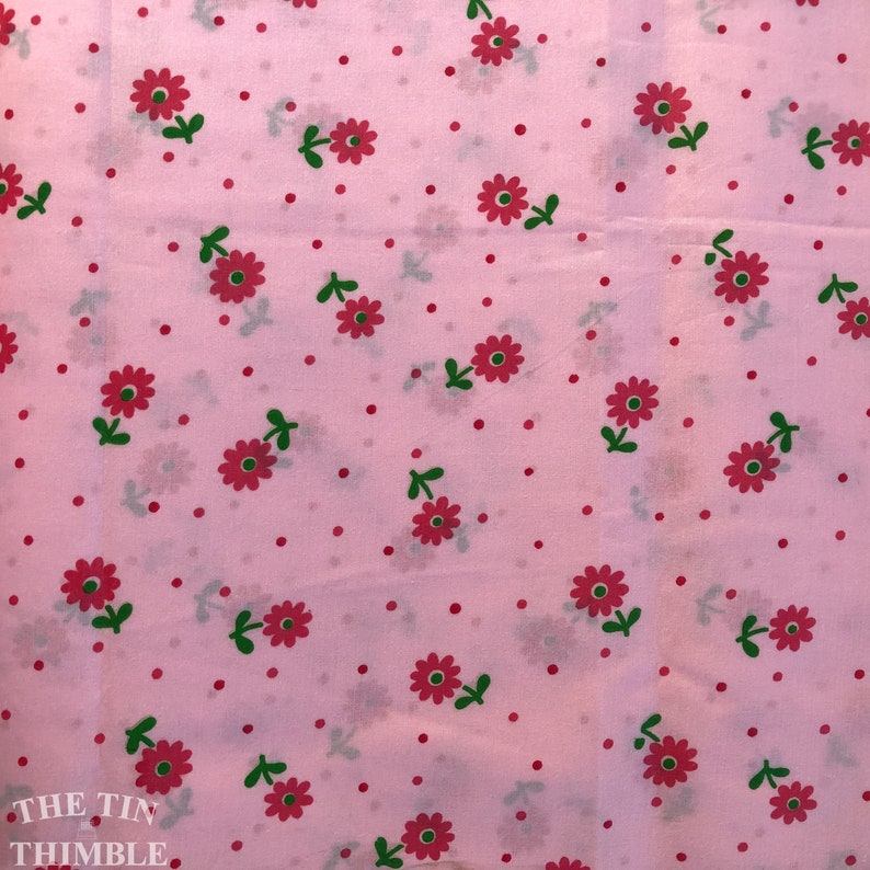 K&ouml;nnte beinhalten: Rosafarbener Stoff mit einem sich wiederholenden Muster aus kleinen roten Bl&uuml;ten mit gr&uuml;nen Stielen und Bl&auml;ttern. Der Hintergrund ist hellrosa mit kleinen roten Punkten.