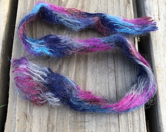 May include: A skein of yarn in shades of blue, pink, and gray. The yarn is soft and fluffy, and it would be perfect for knitting or crocheting.
