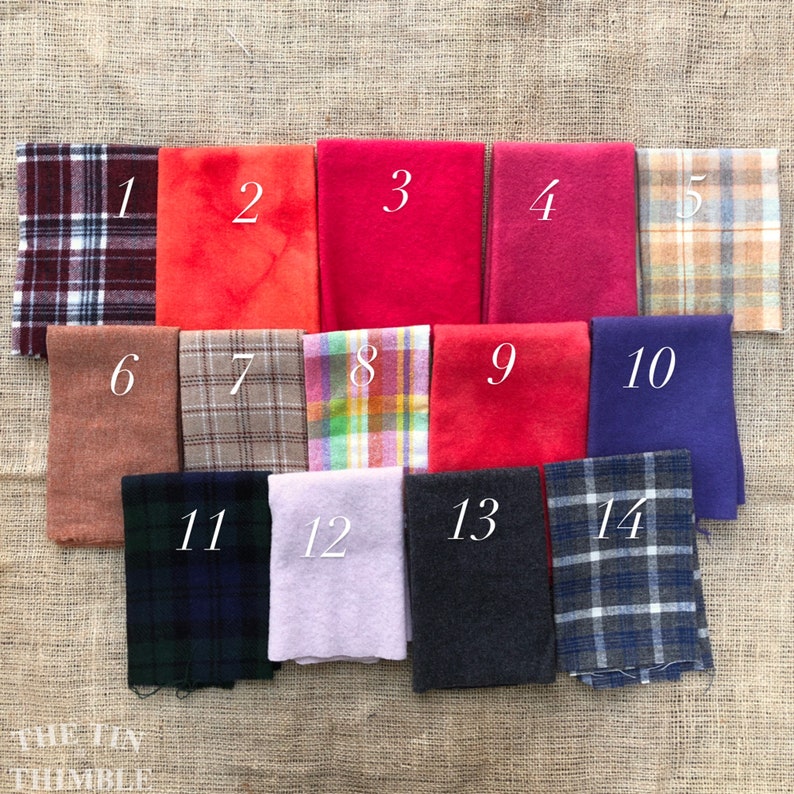 May include: A collection of 14 fabric swatches in various colors and patterns, including plaid, solid, and textured fabrics. The swatches are numbered 1 through 14.