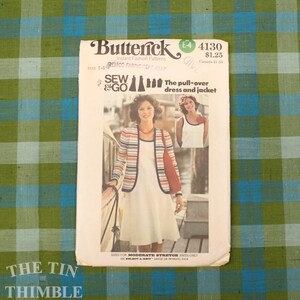 May include: Vintage Butterick sewing pattern for a pull-over dress and jacket. The pattern cover features a woman wearing a white dress and a striped jacket with red, white, and navy blue stripes. The pattern is size 14.