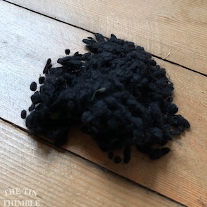 May include: A close-up of a black, fluffy, yarn ball. The yarn is soft and textured, and it is perfect for knitting or crocheting.