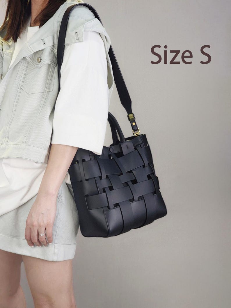 Puede incluir: Bolso tote de cuero negro tejido con una correa para el hombro. El bolso tiene un dise&ntilde;o estructurado con un patr&oacute;n tejido en la parte delantera y los lados. El texto "Size S" es visible en la imagen.