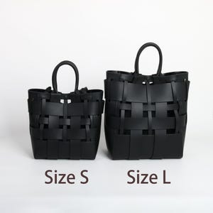 Puede incluir: Dos bolsos tote negros tejidos, etiquetados como "Talla S" y "Talla L". Los bolsos tienen forma rectangular con asa. El patr&oacute;n de tejido es visible y los bolsos est&aacute;n hechos de un material negro liso. El fondo es blanco liso.