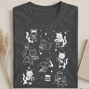 May include: Dark gray t-shirt featuring a white graphic of cartoon cats in various barista roles, such as pouring coffee and serving pastries. The word "Pepper" is printed in the bottom right corner.