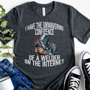 May include: A dark heather grey t-shirt with a welder graphic and the text "I have the unwavering confidence of a welder on the internet".