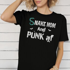May include: Black t-shirt with a white graphic that says "Snake Mom and Punk af" with a green snake and bats.
