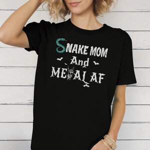 May include: Black t-shirt with a green snake graphic and the text "Snake Mom and Metal AF" in white. The text is stylized with a rock and roll hand gesture.