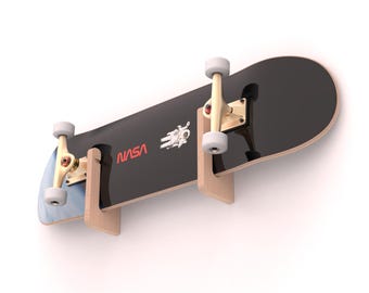 May include: A black skateboard with white wheels and wooden supports. The board features the NASA logo in red and a white astronaut graphic. The skateboard is mounted on a white wall.