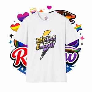 May include: A white short-sleeved t-shirt featuring a central graphic of a lightning bolt colored in yellow, white, purple, and black. The text "THEY/THEM ENERGY" is printed in bold black letters across the lightning bolt design.