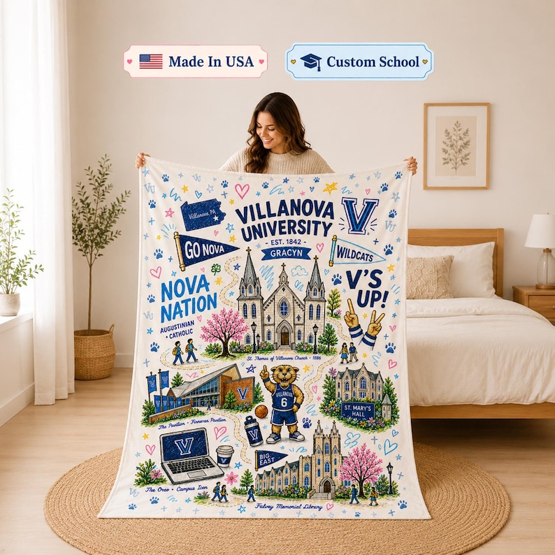 May include: A white throw blanket featuring a colorful Villanova University graphic print. The design includes the university name, campus buildings, a mascot, paw prints, hearts, and text such as Nova Nation, V's Up, and St. Mary's Hall.