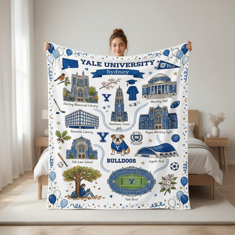 May include: A white throw blanket featuring blue illustrations of Yale University landmarks including Harkness Tower, Sterling Memorial Library, and Yale Bowl. The design includes a bulldog mascot, academic regalia, sports equipment, and the text Yale University Sydney.