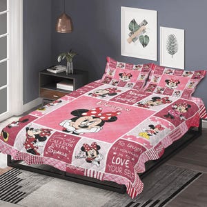 May include: A pink and red Minnie Mouse quilt set with two pillowcases. The quilt features Minnie Mouse in various poses, with text that reads "Boston", "Never Sparkle", "Some days call for extra sparkle", and "To laugh at yourself is to love yourself".